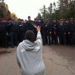 #27 A Woman Kneels Down And Holds Up A Feather While Facing Police Moving In To Break Up Anti-Fracking Protesters In New Brunswick, October 2013